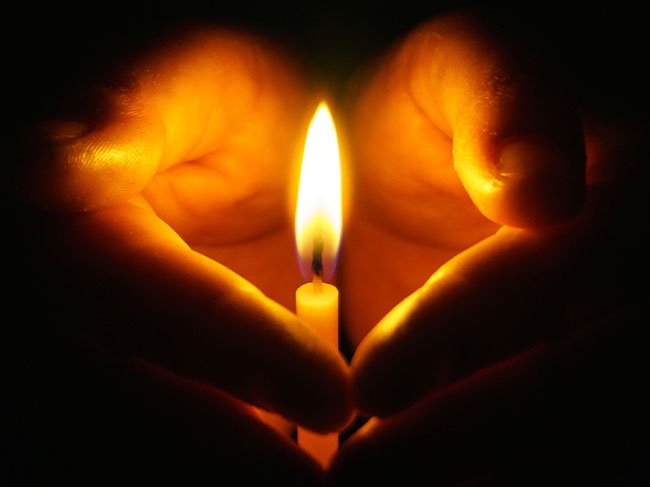 manos en meditacion con velas encendidas